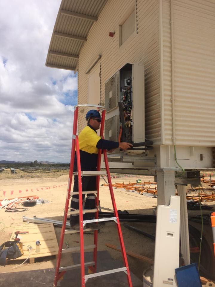 A Man on a Ladder Working on a Building — Legit Air Conditioning & Refrigeration in Garbutt, QLD