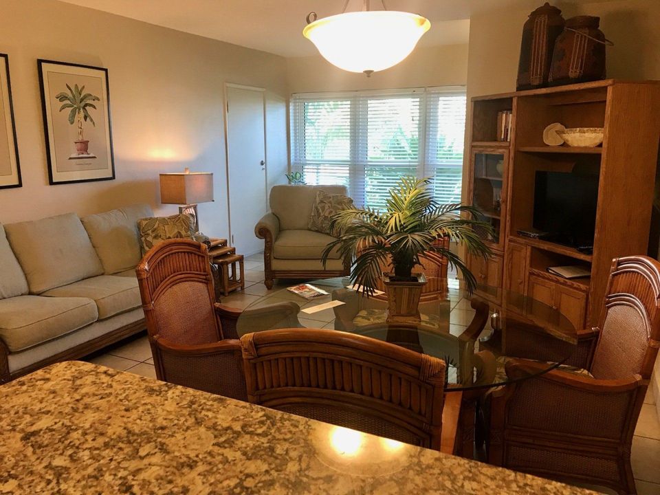 Cozy living room with wicker chairs, beige sofa, wooden TV cabinet, and a glass coffee table near bright windows