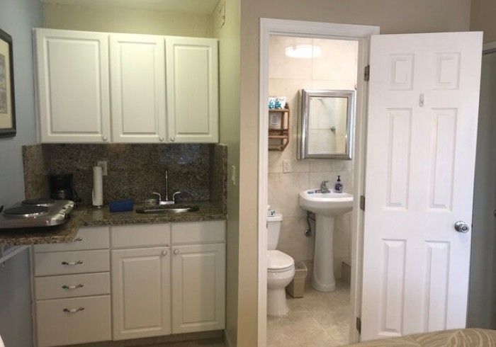 Bathroom vanity and open doorway to a small white bathroom with sink and toilet.