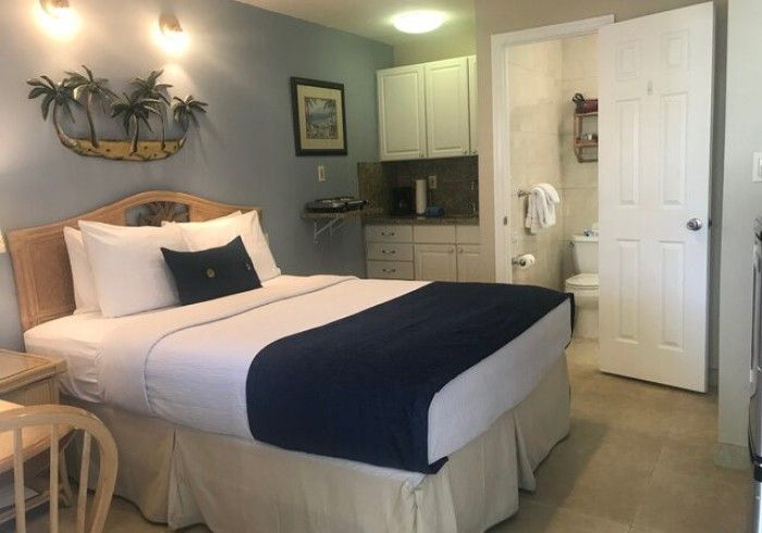 Bedroom with queen bed, navy accents, and a small kitchenette area in the corner