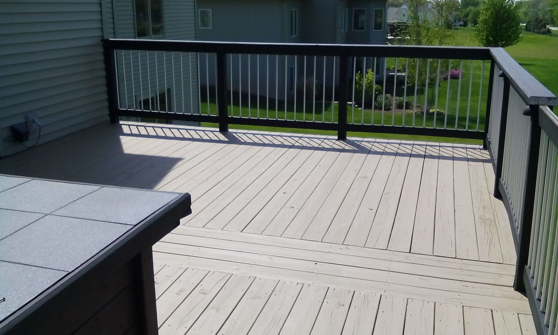 A deck with a black railing and a gray table