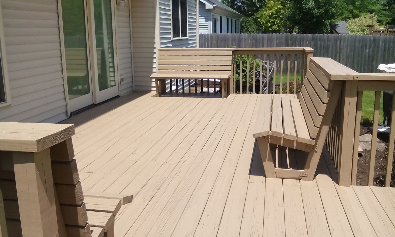 A wooden deck with a bench and chairs on it