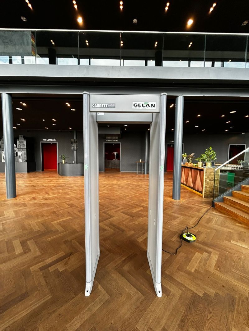 Een metaaldetector staat op een houten vloer in een grote kamer.