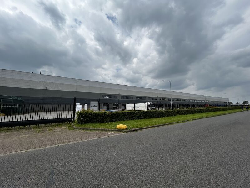 Op een bewolkte dag staat er een groot gebouw langs de weg.