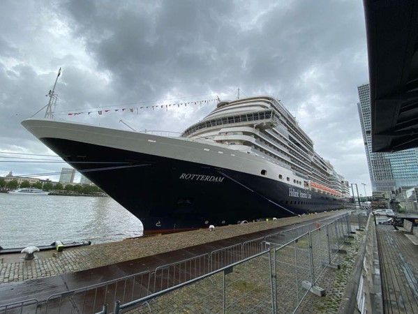 Een groot cruiseschip ligt op een bewolkte dag aangemeerd in een haven.