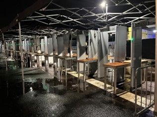Een rij tafels en stoelen onder een tent 's nachts.