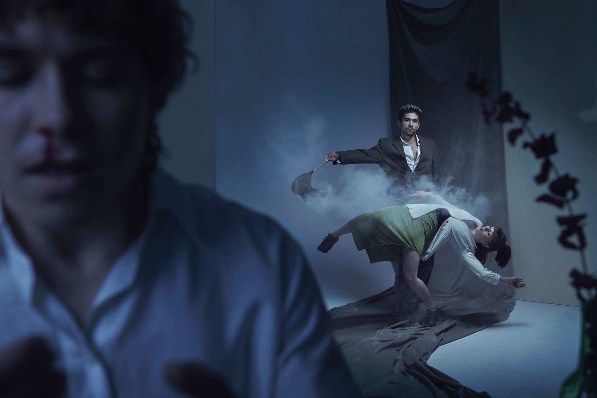 Three circus artists in motion with one in soft focus. Smoke flies while they pose dynamically.