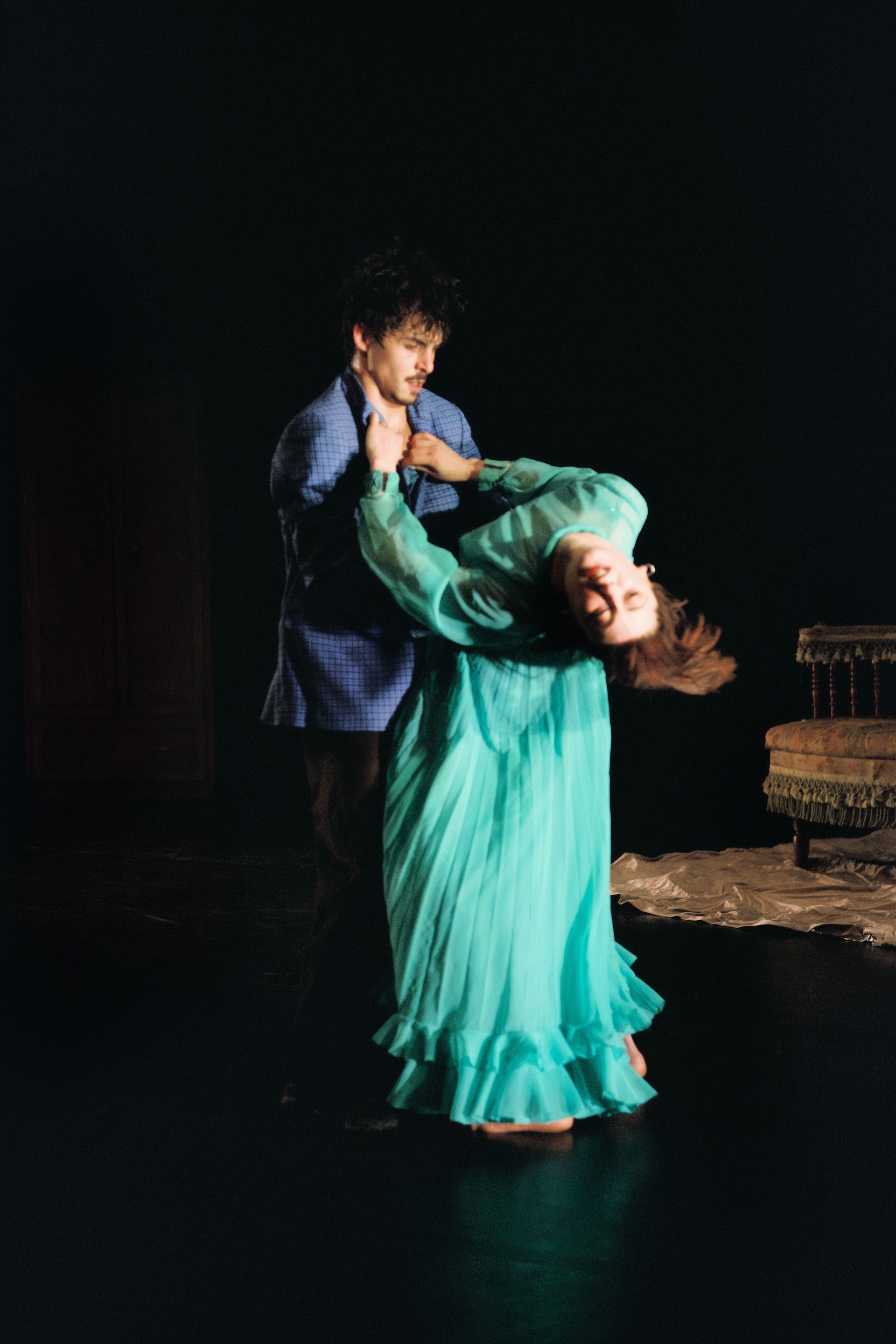 Two people dressed formally embrace. One arches away throwing her head back.
