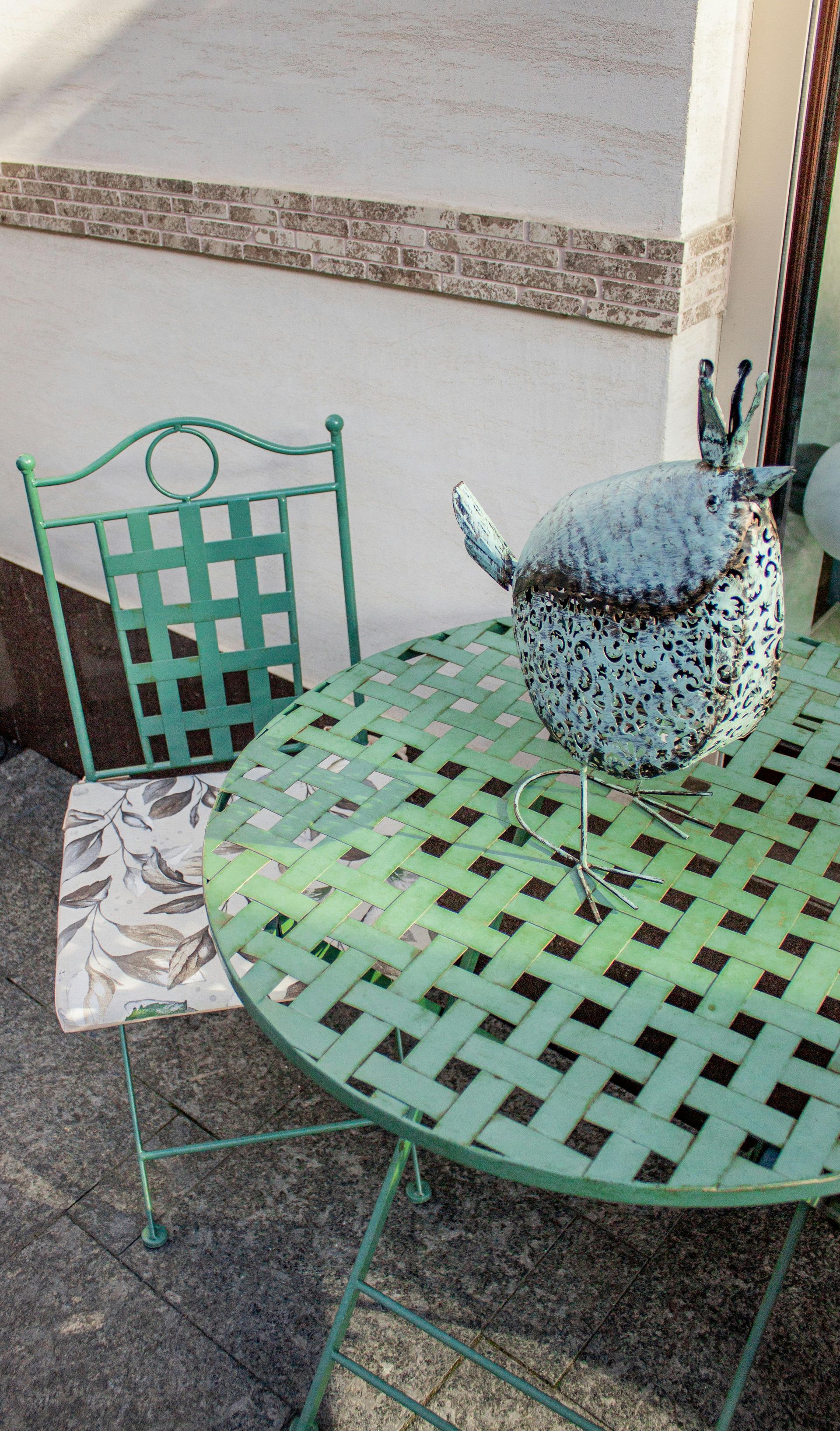 Mint-green patio table and chair with a blue potted plant on a balcony terrace