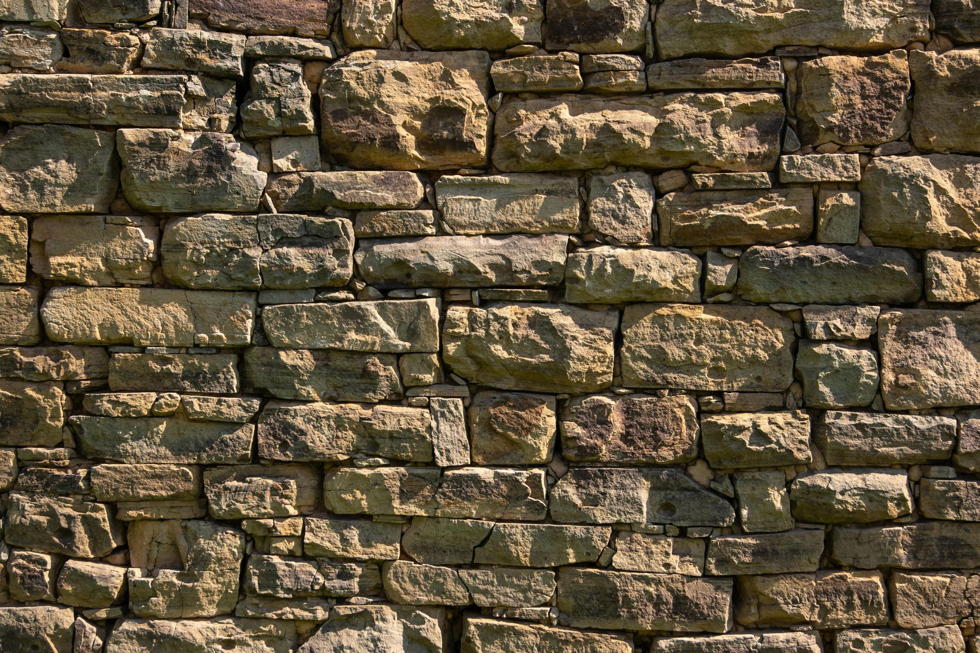 Weathered stone wall with irregular brown and gray bricks.