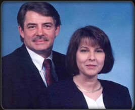 Two formally dressed people posing against a blue studio backdrop.