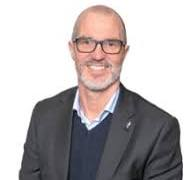 A man with a beard and glasses is wearing a suit and smiling. jonathan Kay