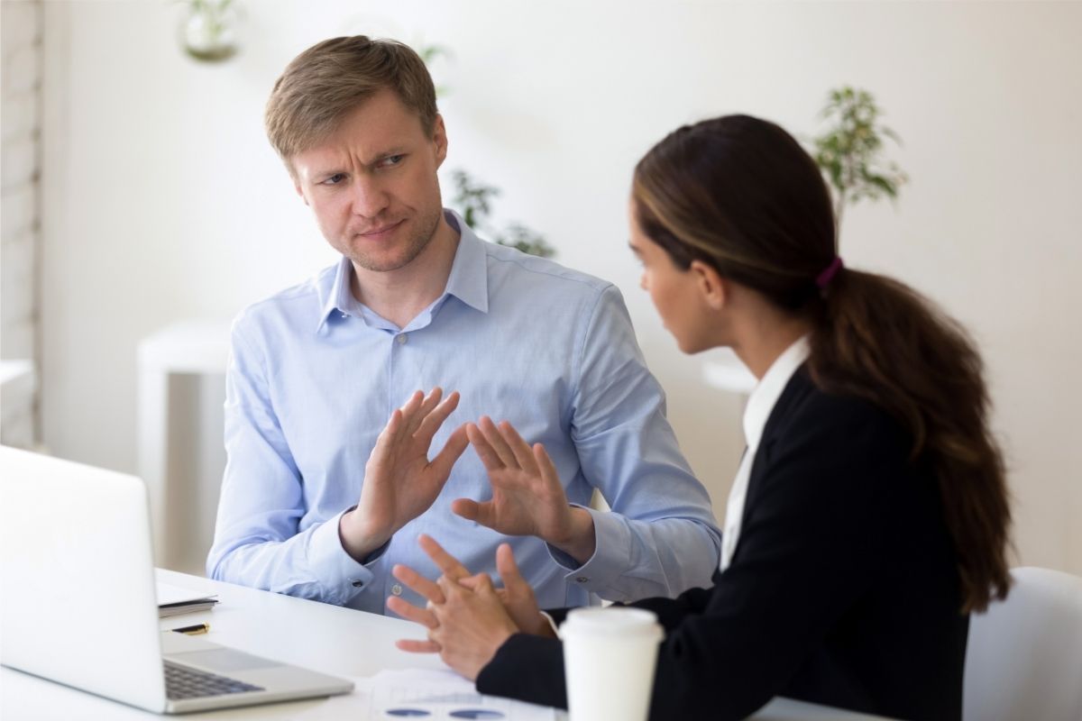 A man and a woman are sitting next to each other at a table talking to each other.