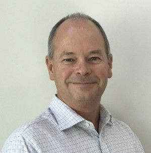 A man in a plaid shirt is smiling for the camera. Mark MacDonald