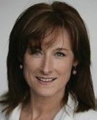 A woman with long brown hair and earrings is smiling for the camera. Pam Cronin