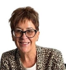 A woman wearing glasses and a leopard print jacket is smiling. Penny Holder