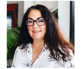 A woman wearing glasses and a white shirt is smiling for the camera. Raine Selles