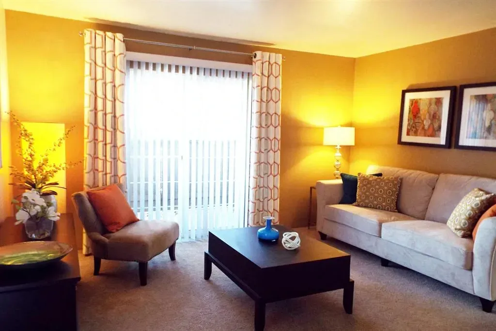 Living room with sofa, chair, coffee table, and sliding glass door with blinds.