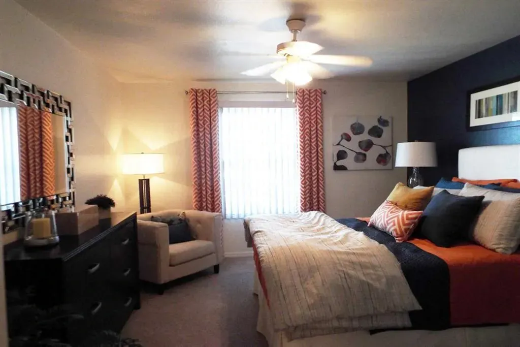 Bedroom with a queen-size bed, dresser, and armchair.