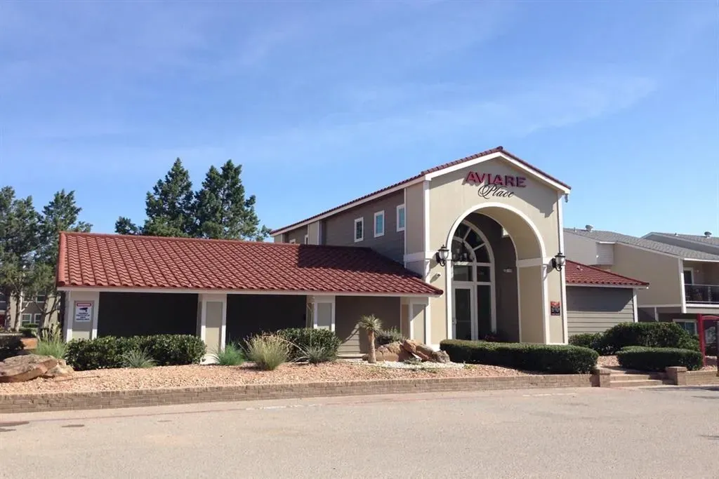 The entrance to Aviary Place apartments features a large arched entryway with the property name above.