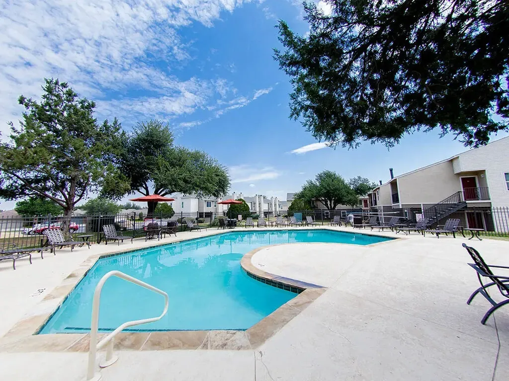 A beautiful swimming pool with lounge chairs and umbrellas in a multifamily property.