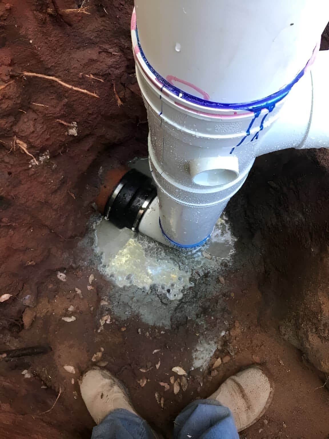 A Person Is Standing Next To A Pipe In The Dirt — Nudges Plumbing In Dubbo, NSW