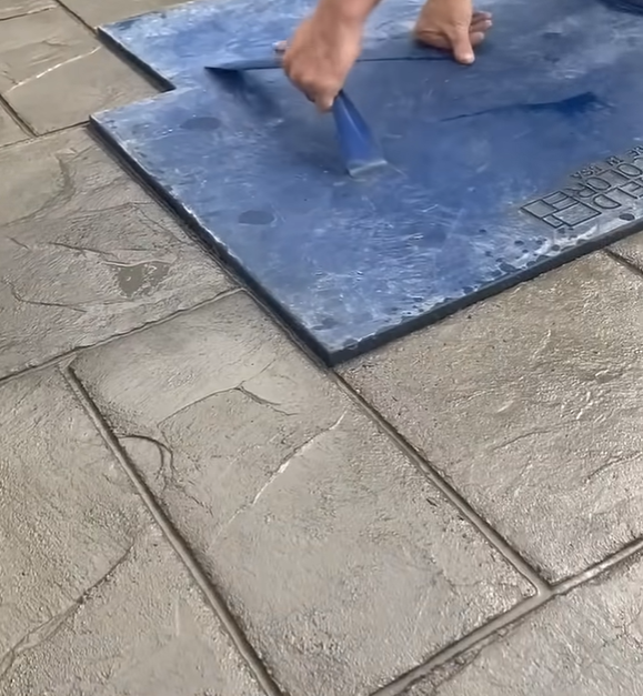 concrete contractor finishing a patio with a concrete stamp tile design