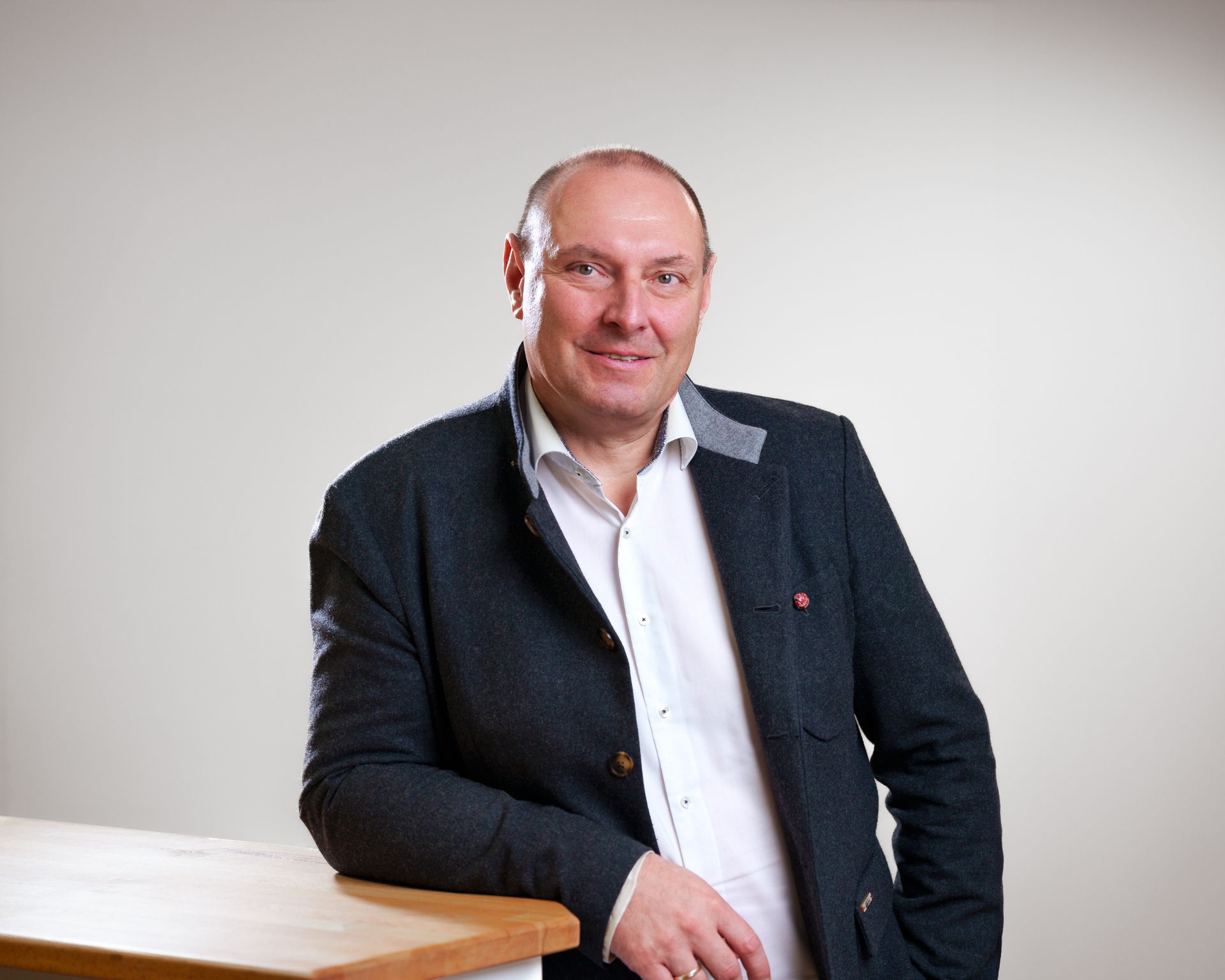 A man in a suit is leaning on a wooden table