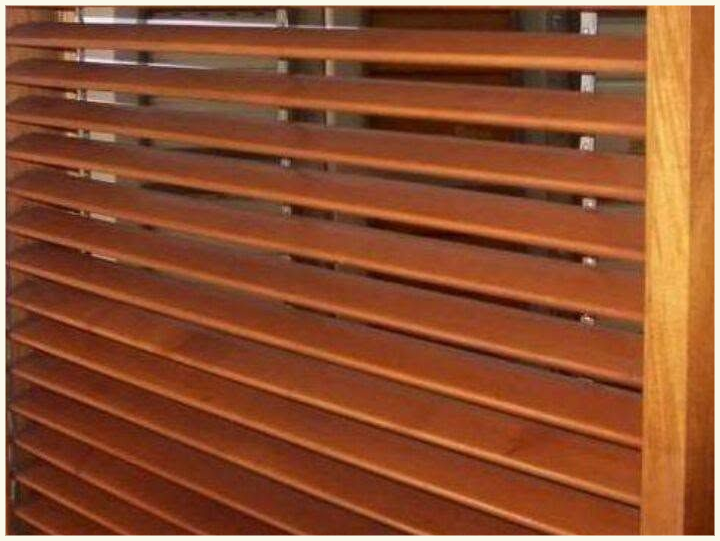 Persianas de madera con listones horizontales, parcialmente abiertas para dejar pasar la luz que hay detrás.