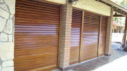 Puertas enrollables de madera en un escaparate o garaje con paredes de ladrillo y piedra.