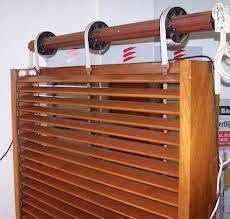 Persianas de madera que se elevan mediante un sistema de poleas con cordones y rodillos en la parte superior.