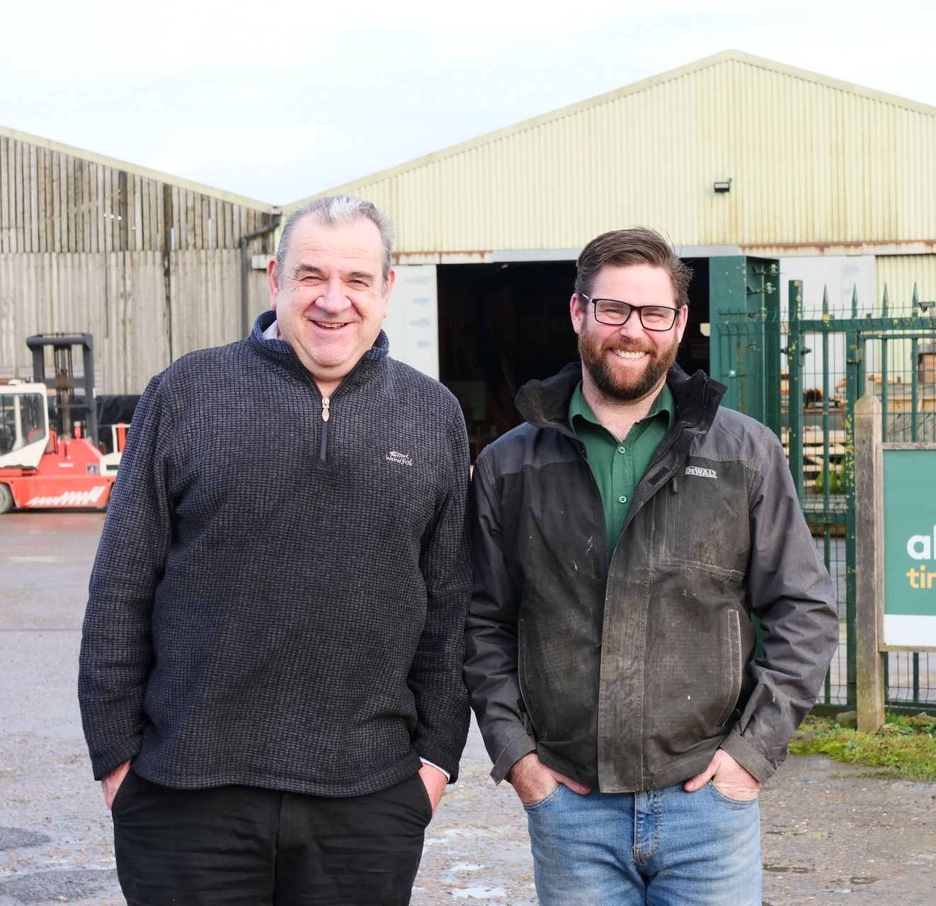 Two Generations standing next to each other in front of  Allan Binks Timber Merchants