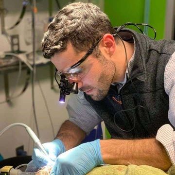 Technician in safety glasses and gloves welding with a bright arc at a workbench