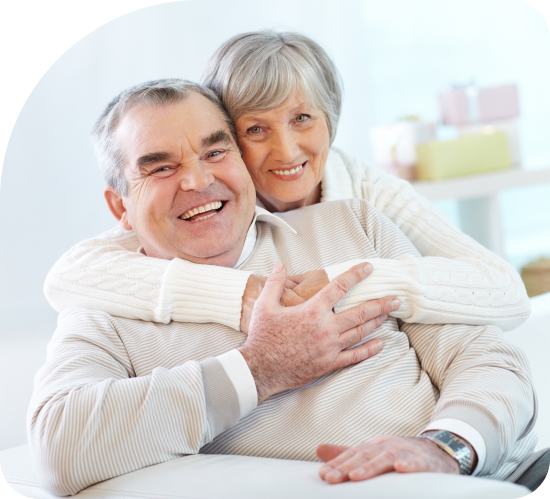 A woman is hugging an older man on a couch