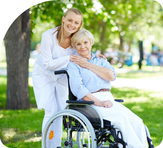 A woman is standing next to an older woman in a wheelchair.