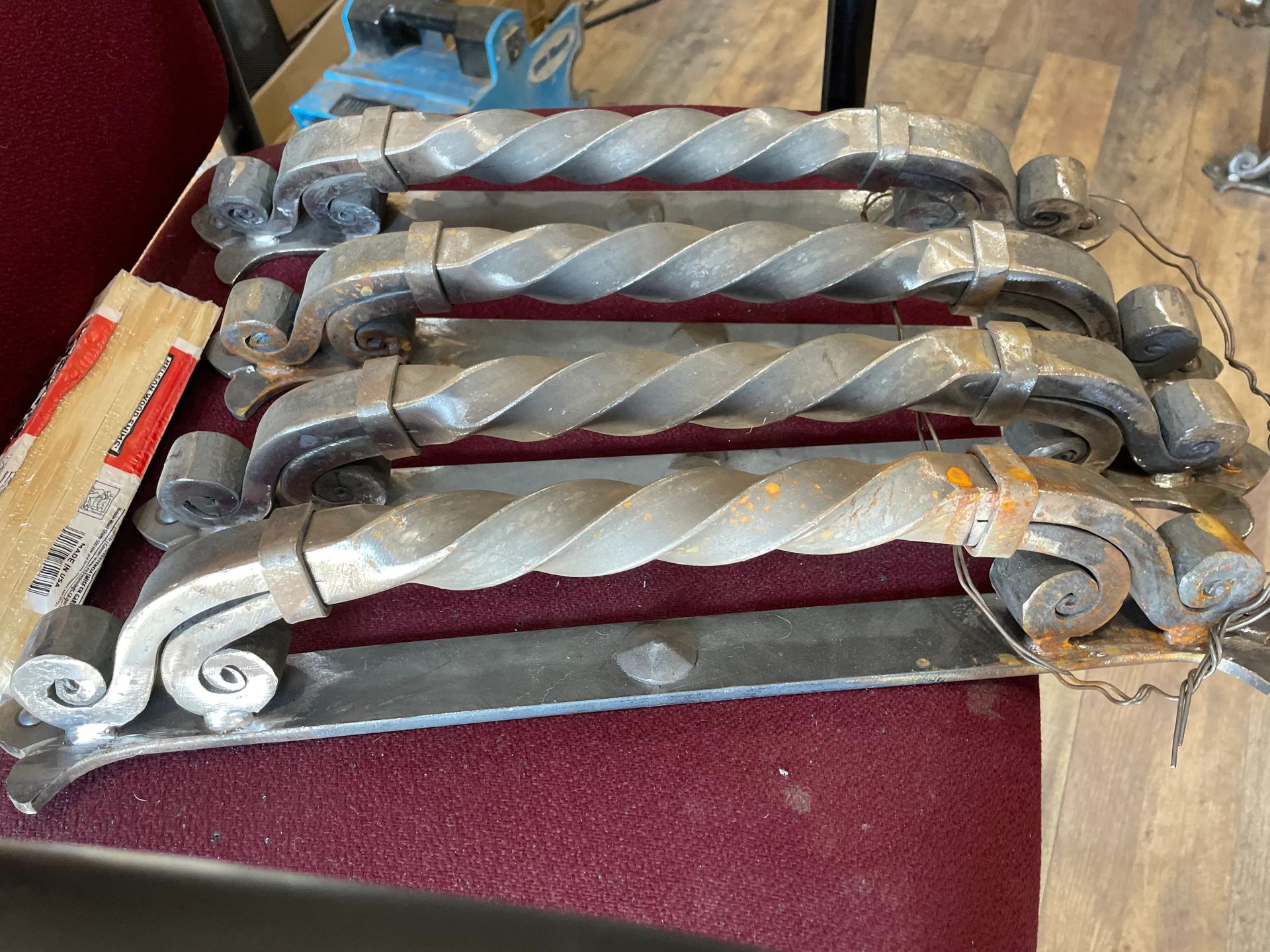 Four twisted metal door handles with ornate scrollwork, resting on a maroon surface.