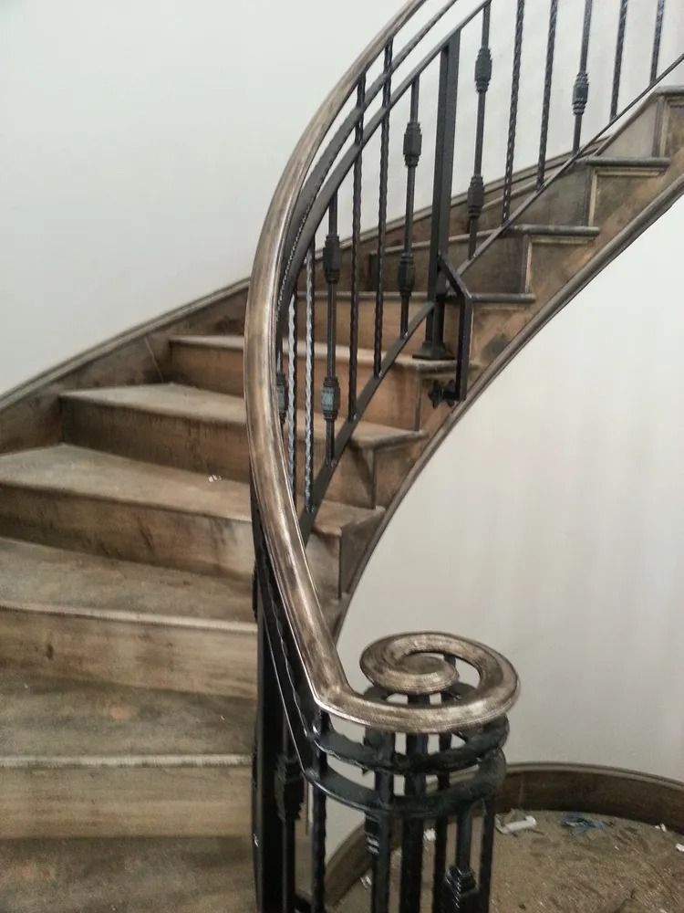 Wooden spiral staircase with black metal railing.