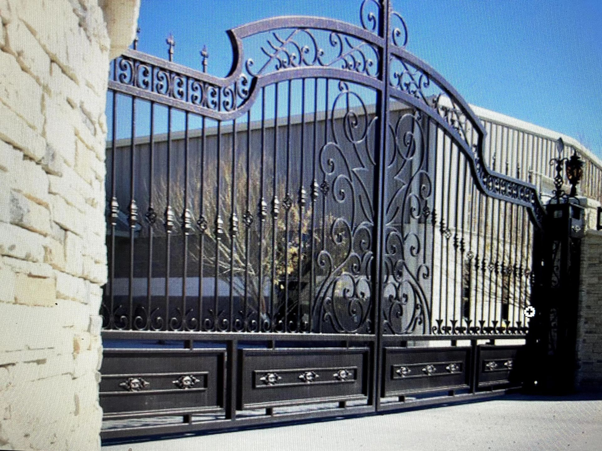Ornate black wrought iron gate with decorative scrollwork, set in a stone wall, leading to a building.