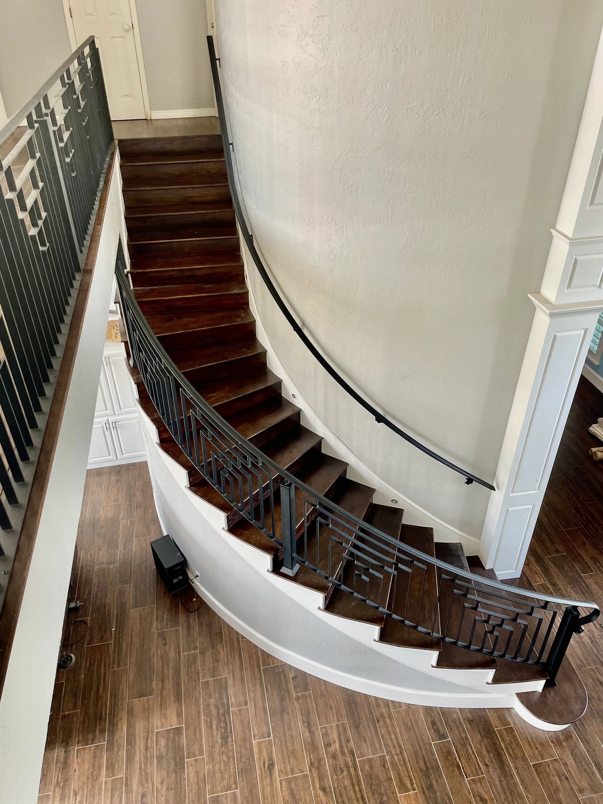 Dark wood curved staircase with black metal railings.