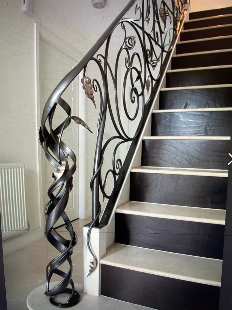 Staircase with ornate wrought iron railing, dark wood steps, and marble accents.