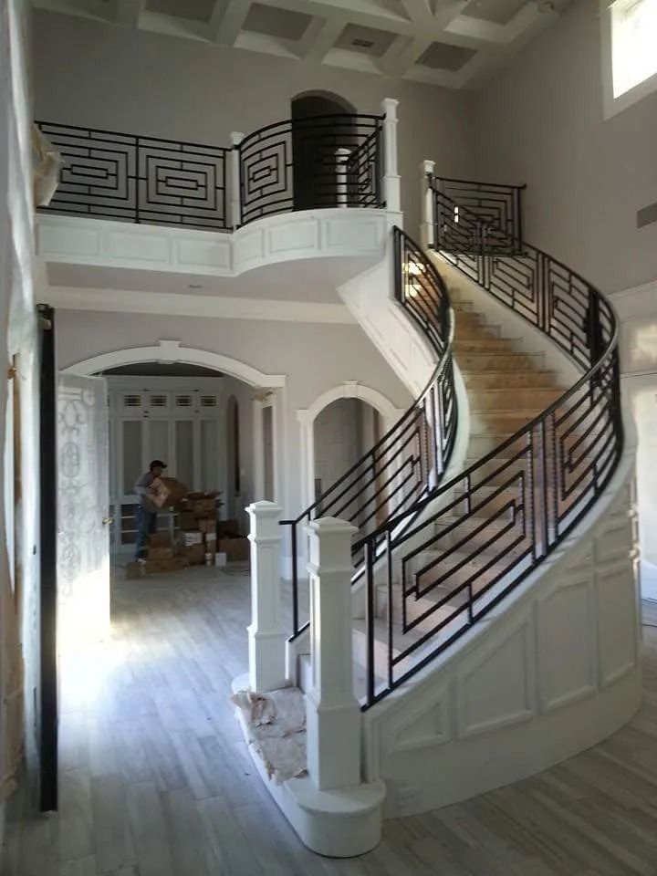 A curved staircase with black metal railings in a two-story home, under construction.