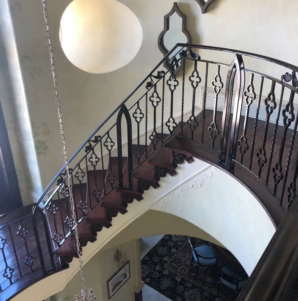 Staircase with dark wood steps and ornate black railing, viewed from above.
