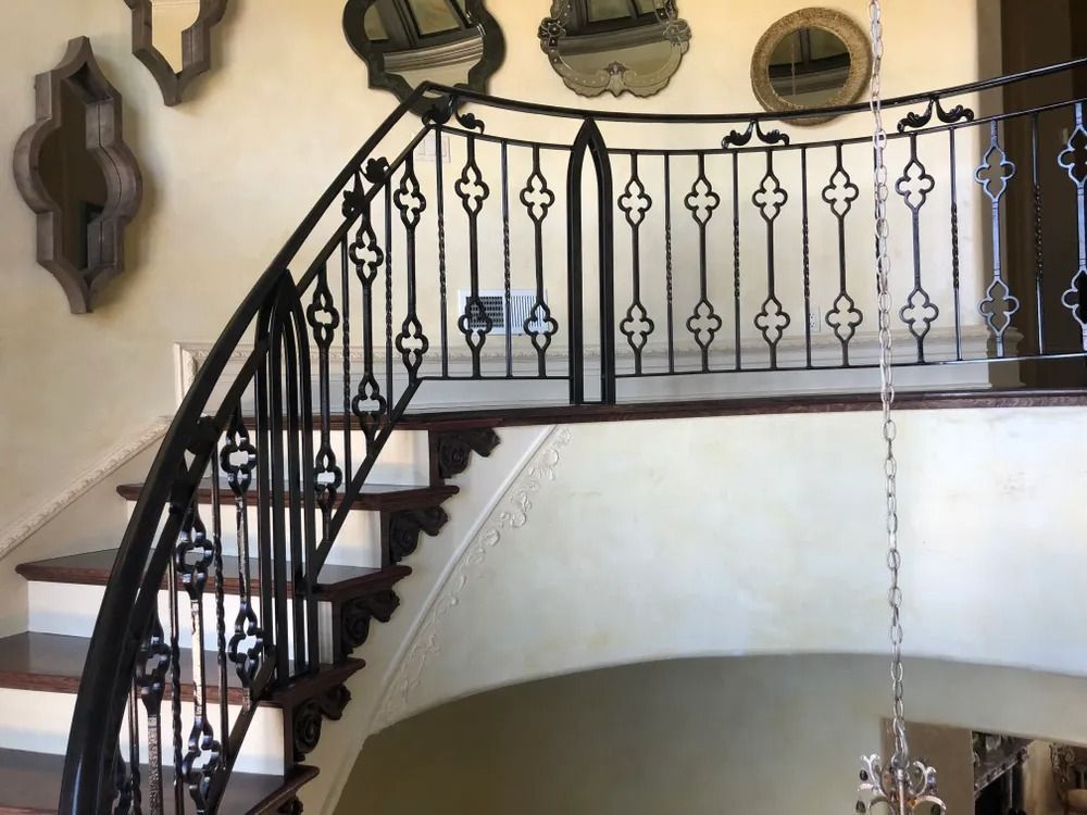 Wrought iron banister and staircase with wood steps, cream-colored walls, and decorative mirrors.