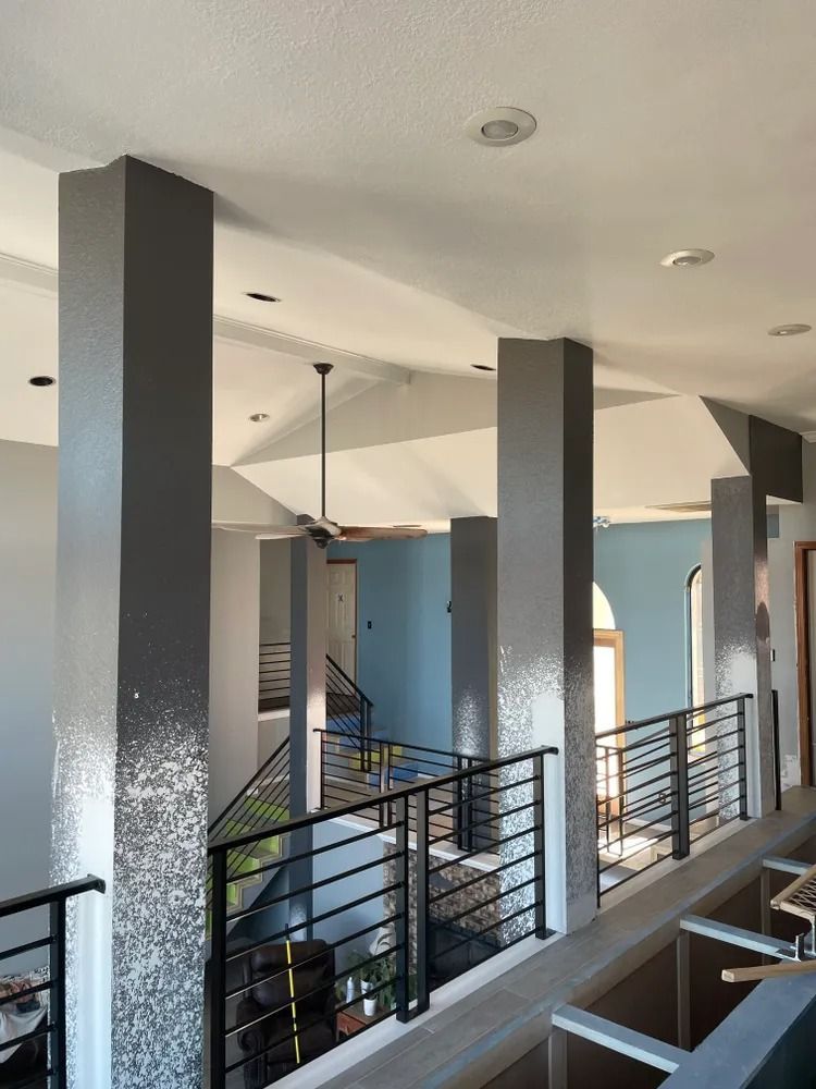 Interior view of a modern building with gray columns, black railings, and a blue wall in the background.