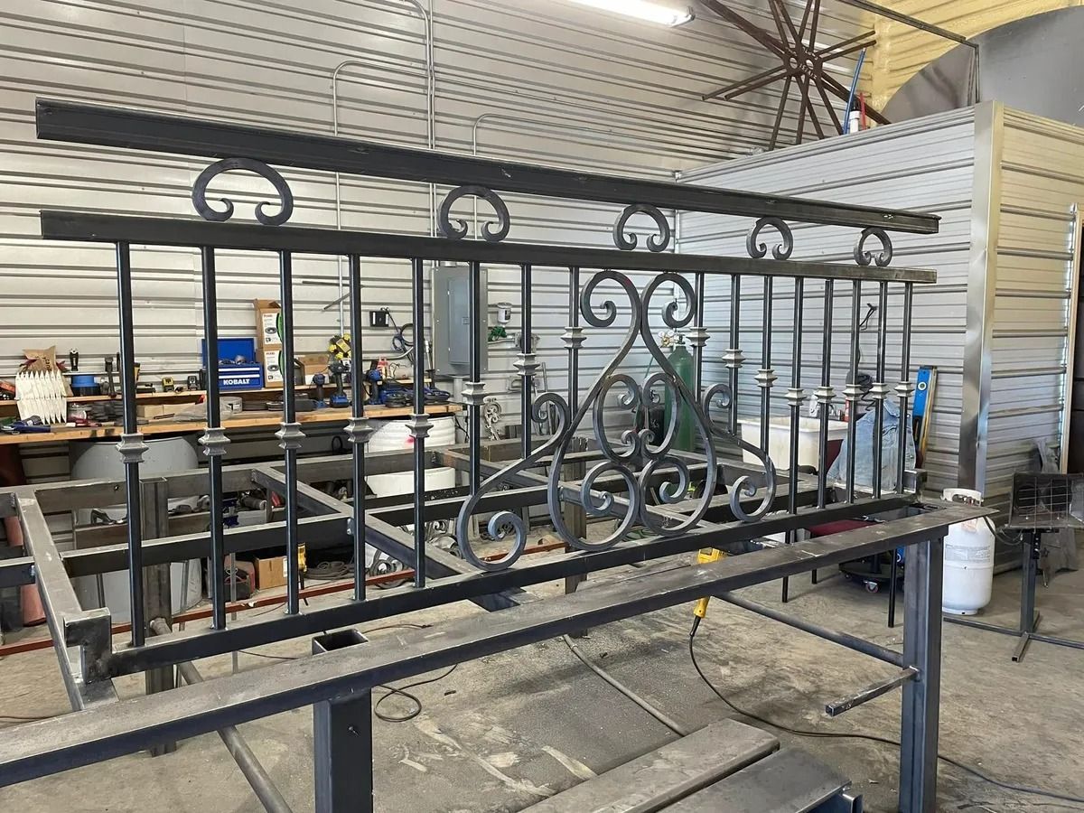 Black wrought iron railing on a metal workbench in a workshop.