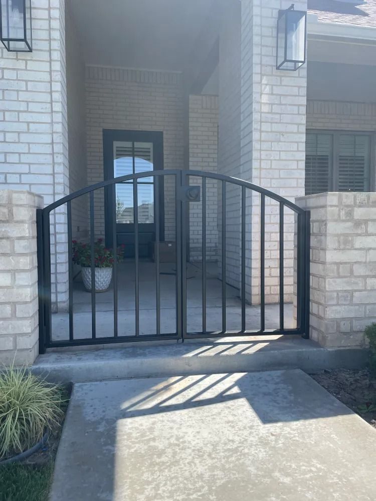 Black metal gate in front of a brick home's entryway.