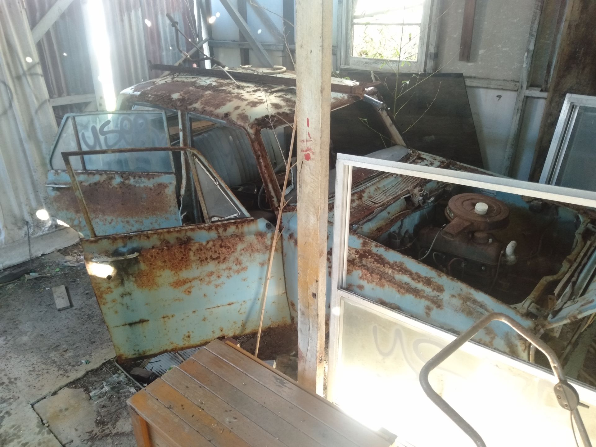 An Old Rusty Car Is Sitting In A Room Next To A Wooden Table — Tweed Byron Recycling In Byron Bay, NSW