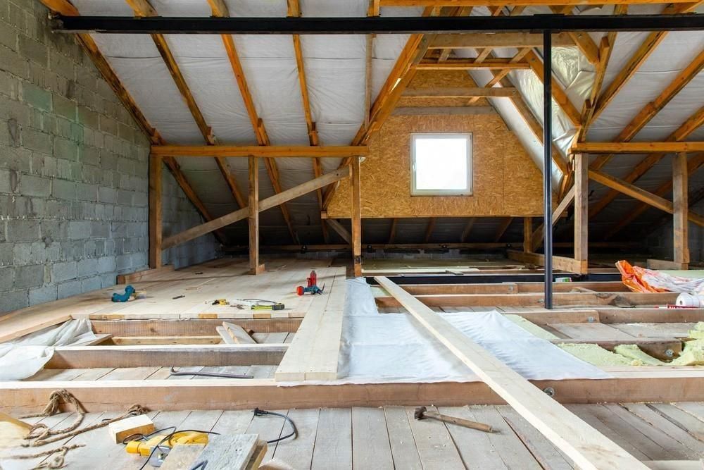 An attic under construction with wooden beams and a window.