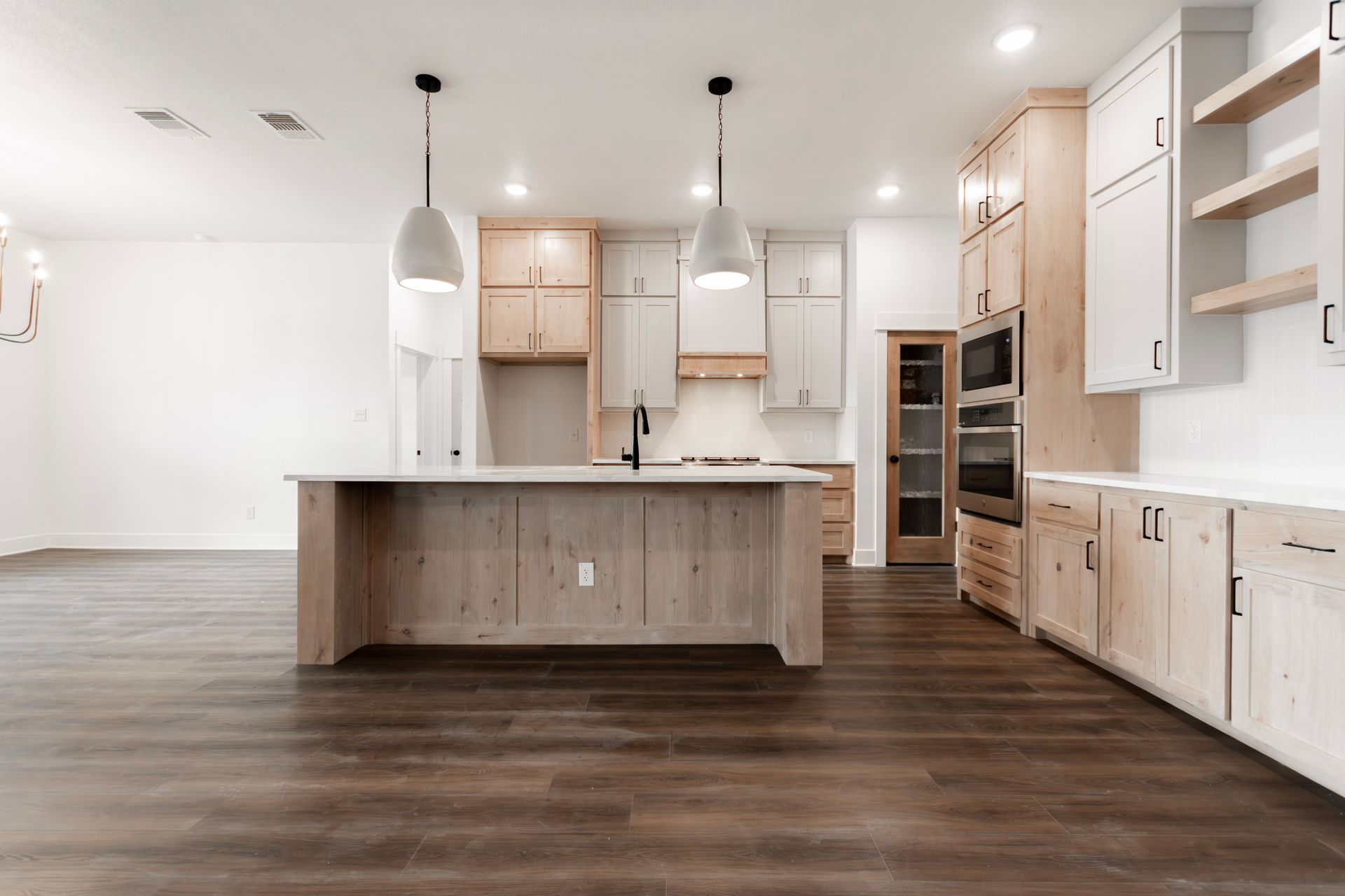 Modern kitchen with wood island, light cabinets, dark floors, and pendant lights.