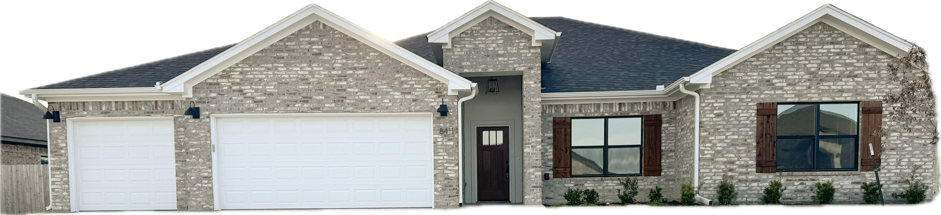 A house with a stone exterior, black roof, and white garage doors.